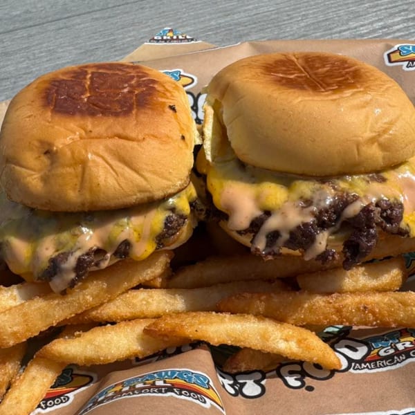 Two Surf Dawgs Grill cheeseburger sliders with special sauce and a side of golden french fries.