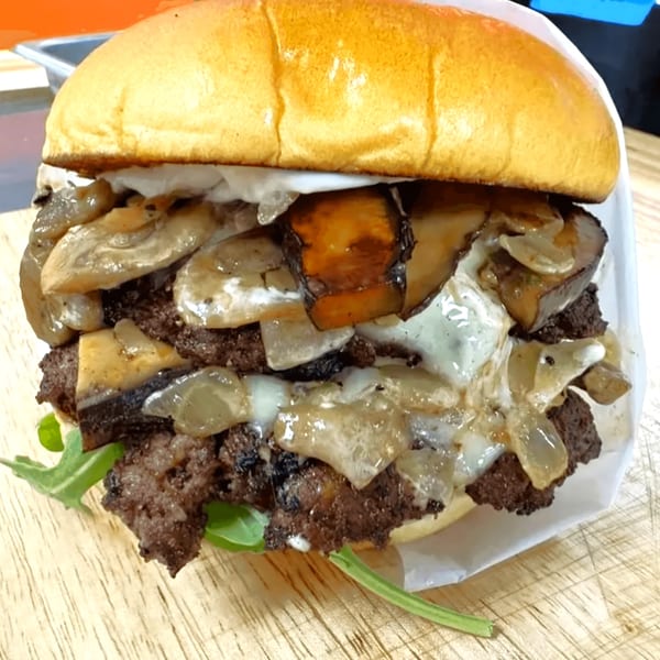 A Surf Dawgs Grill burger with two patties, melted cheese, sautéed mushrooms, and onions.